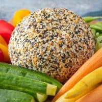 Everything bagel cheese ball on a platter with carrots and peppers