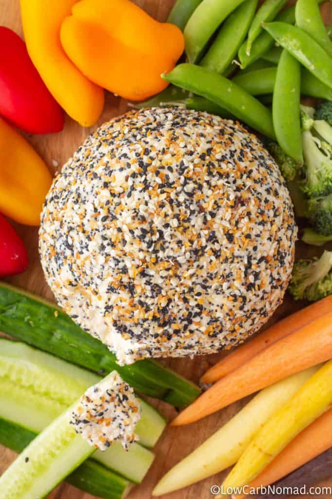 Everything bagel Cheese ball on a platter with carrots, cucumbers, peppers and sugar snap peas