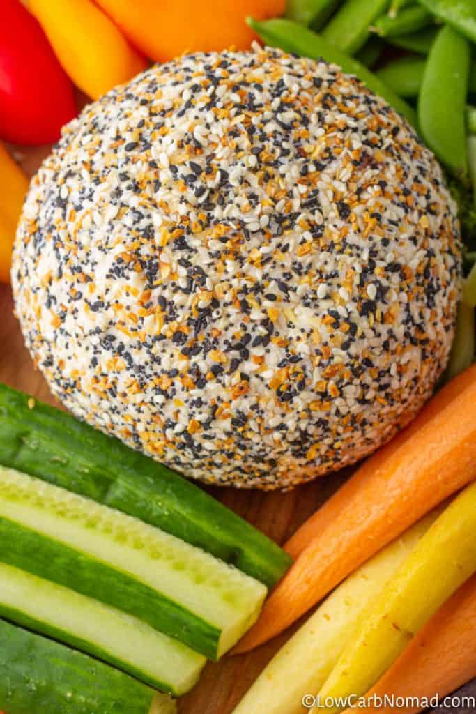 Everything bagel Cheese ball on a platter with carrots, cucumbers, peppers and sugar snap peas