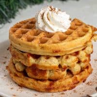 Gingerbread Chaffles on a white plate topped with keto whipped cream.