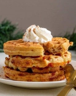 3 gingerbread chaffles on a white plate with a dolp of whipped cream on top