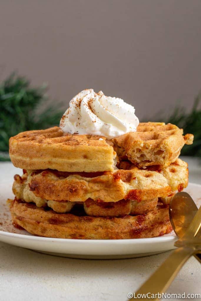 3 gingerbread chaffles on a white plate with a dolp of whipped cream on top