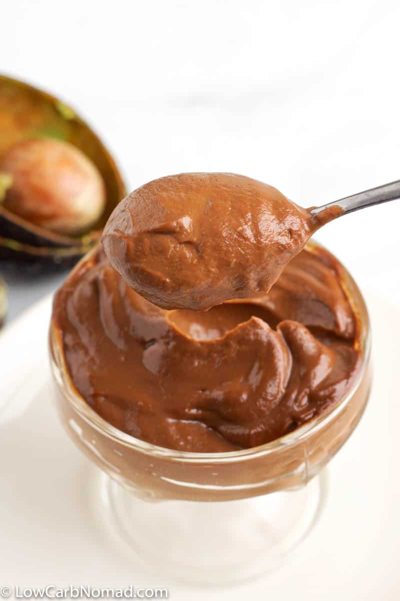 A bowl of keto chocolate pudding being scooped out with a spoon.