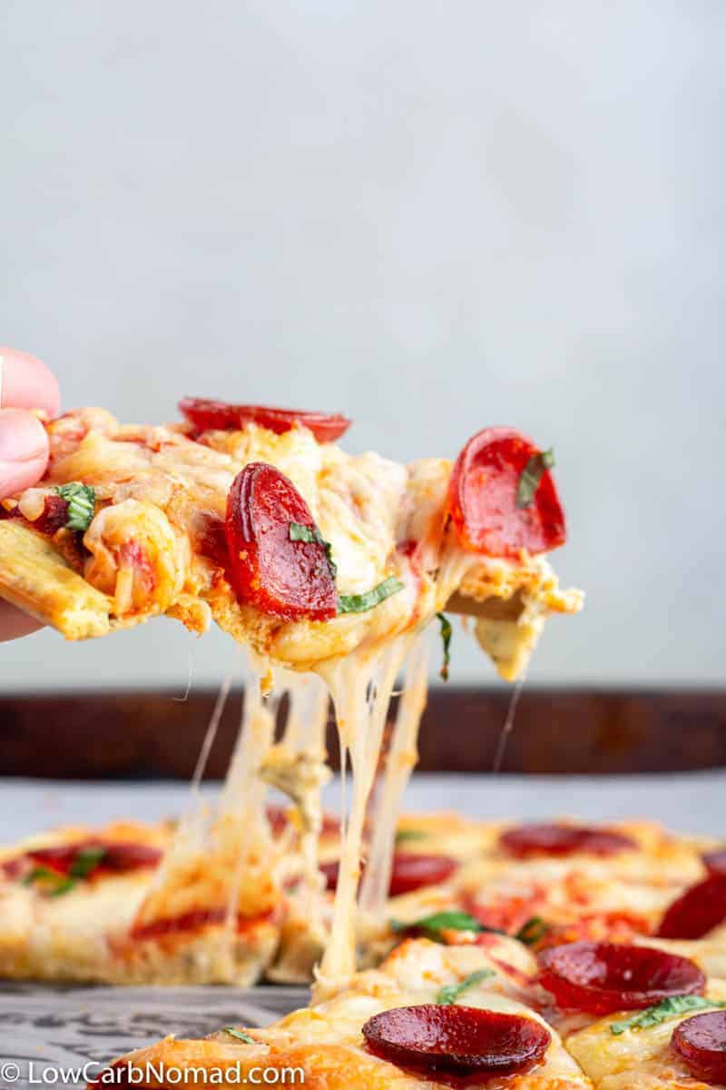 A slice of keto pizza with keto pizza crust topped with cheese and pepperoni