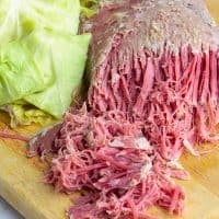 Crockpot corned beef and cabbage on a wooden cutting board ready to be served