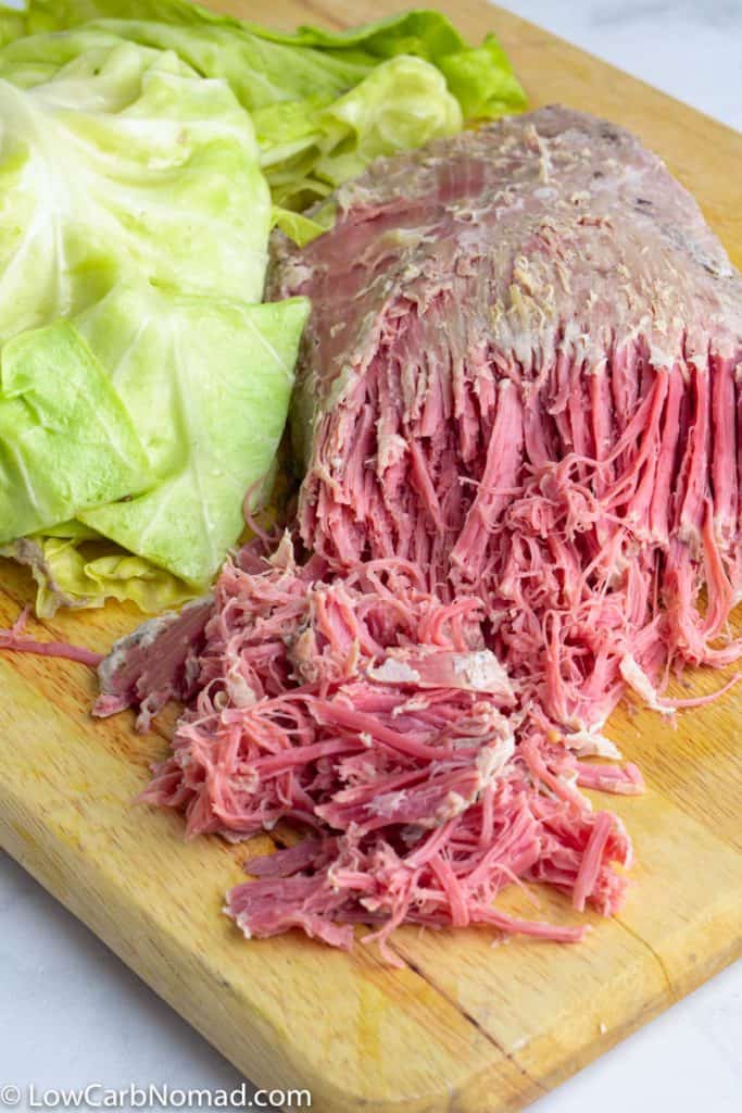 Crockpot corned beef and cabbage on a wooden cutting board ready to be served