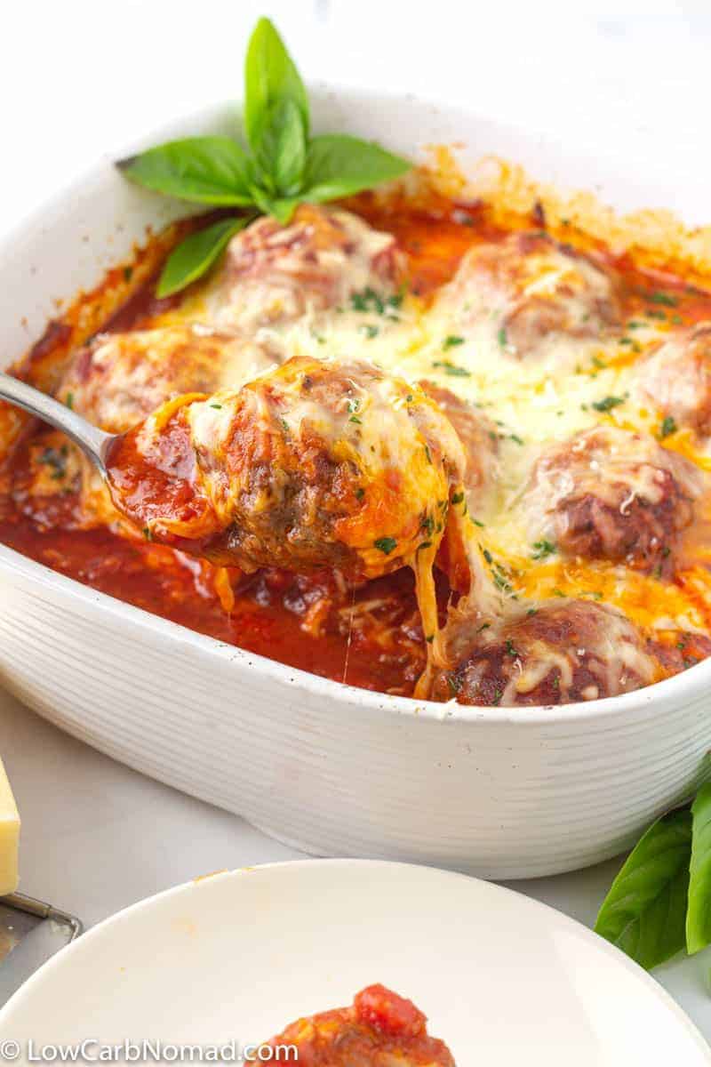 Ground beef formed into balls with tasty sauce topped with melty cheese in a white serving dish