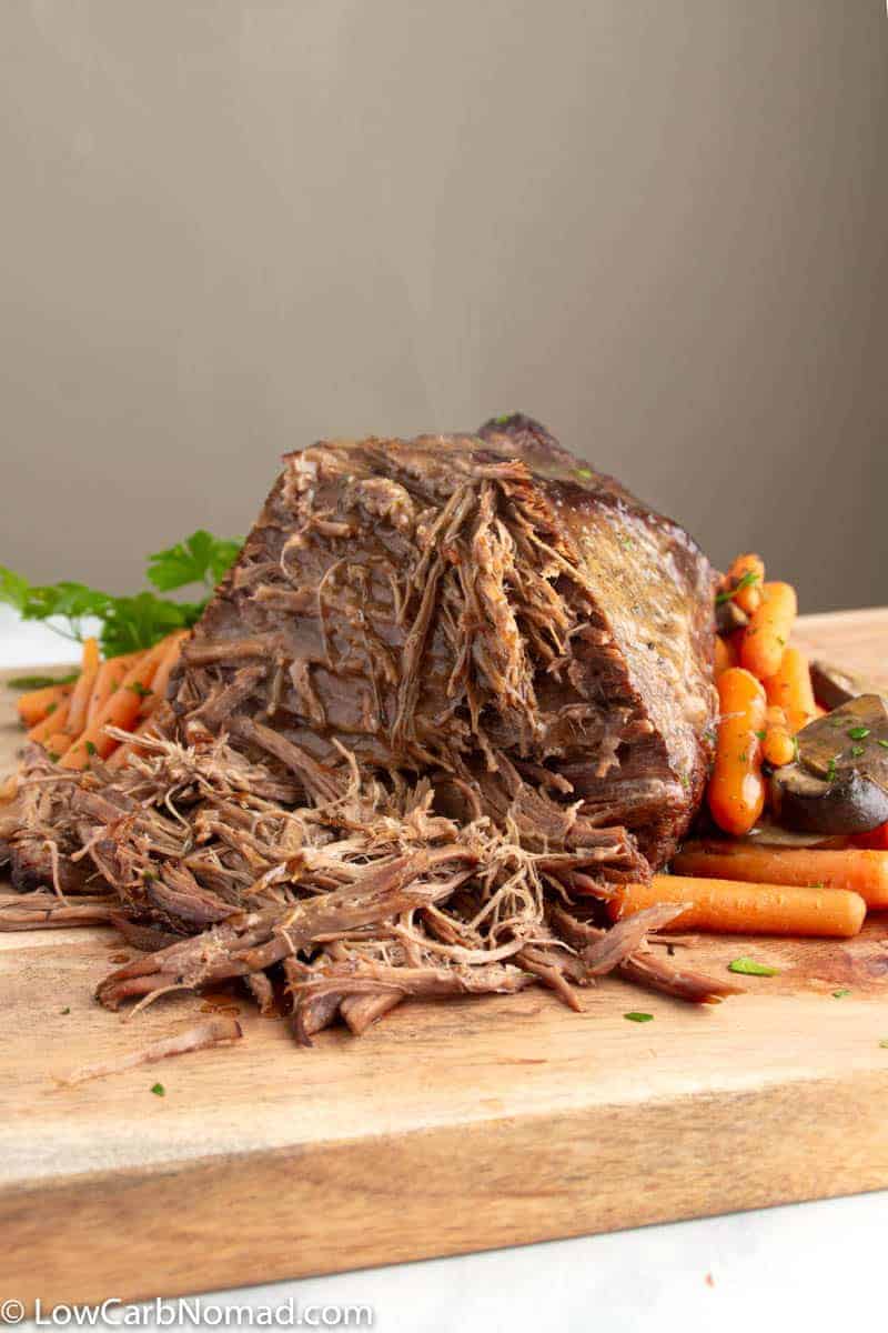 Instant Pot Pot Roast with veggies being sliced on a butcher block