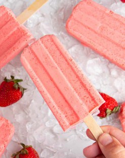 Hand holding a strawberry keto popsicle