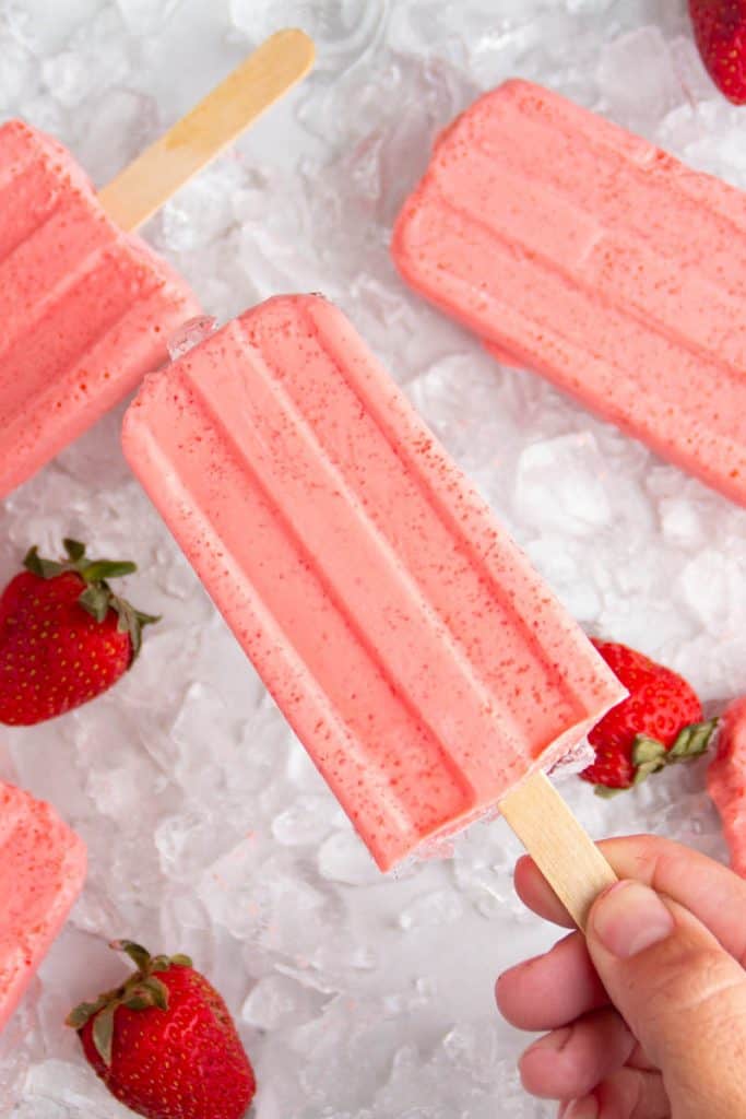 Hand holding a strawberry keto popsicle