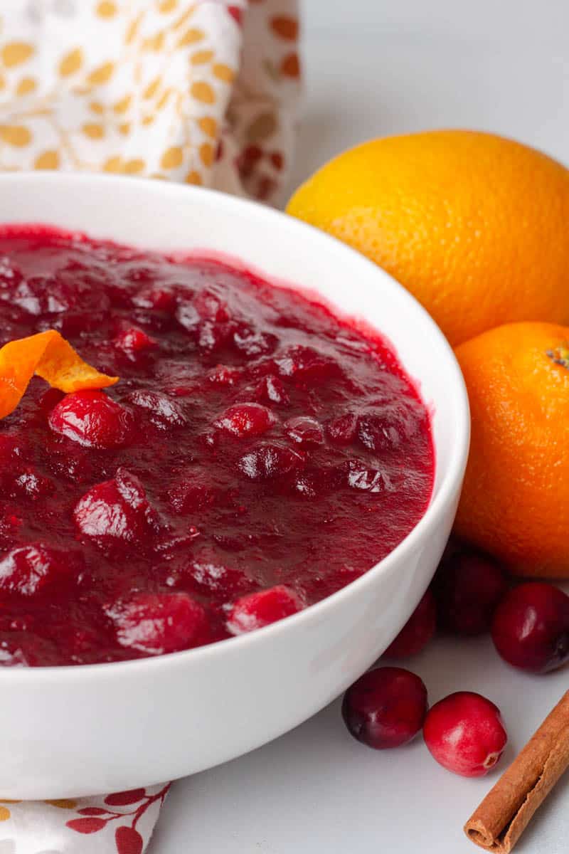 close up photo of keto cranberry sauce in a bowl with oranges next to it