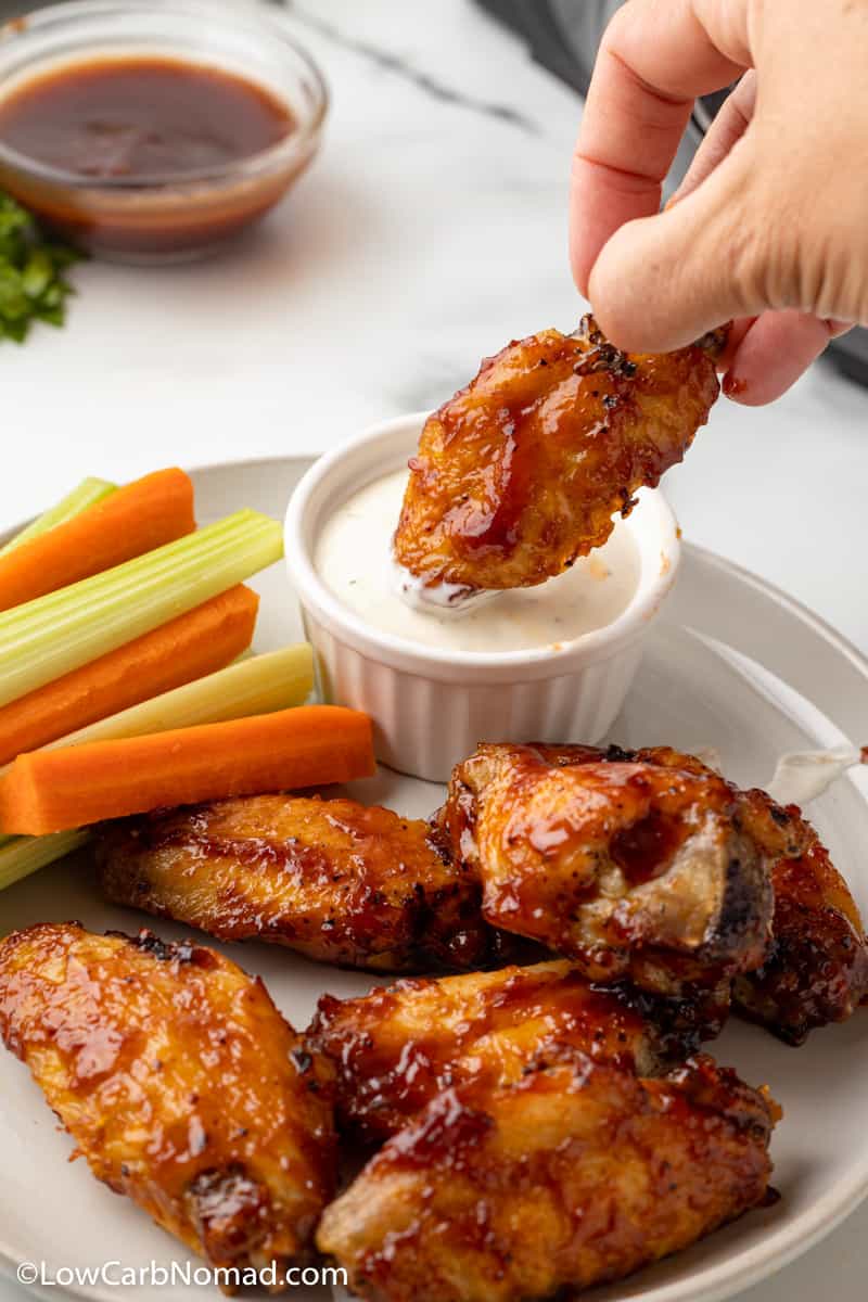 keto BBQ wings being dipped in ranch dressing
